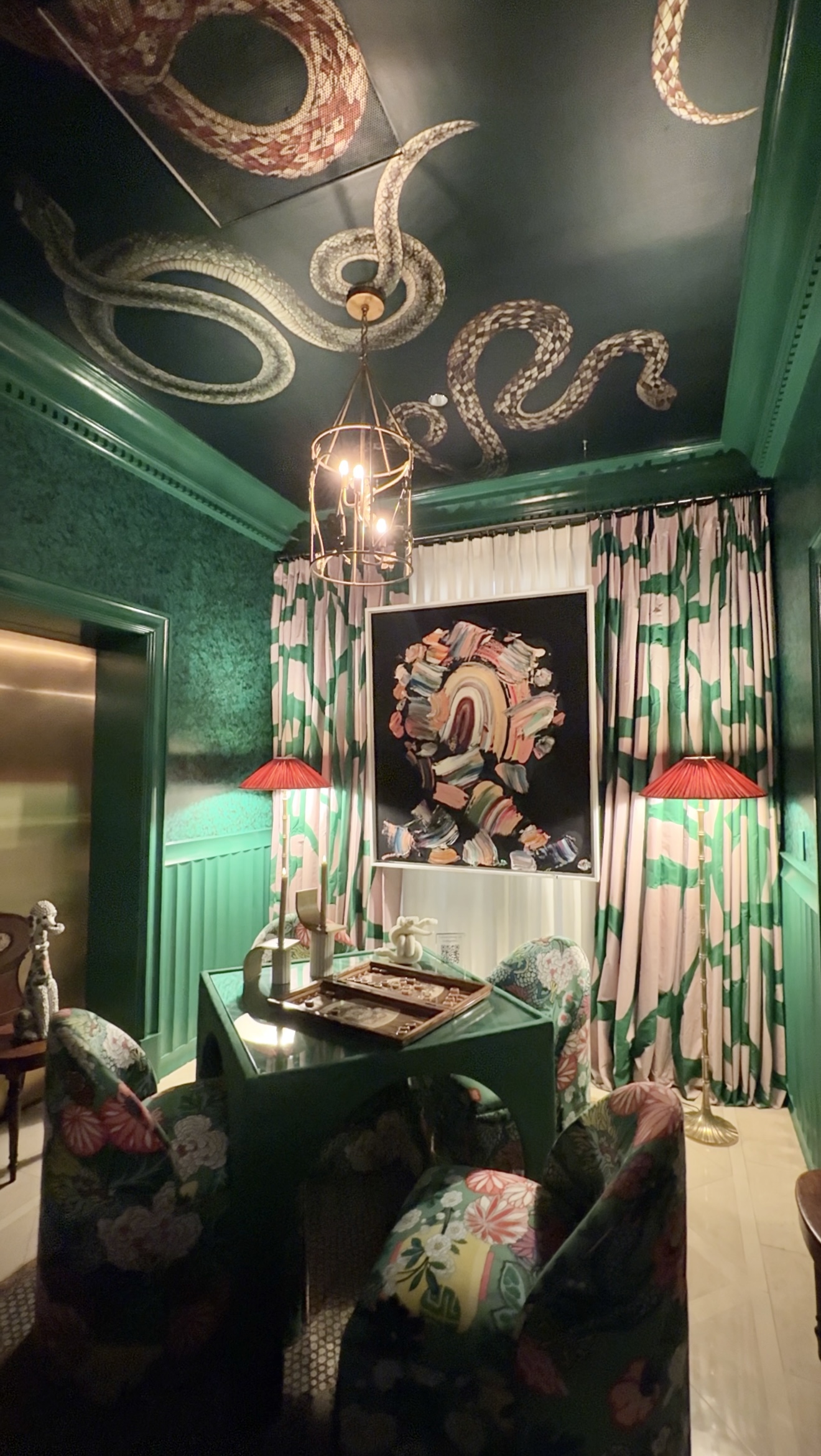 A vibrant green designer room featuring bold color, pattern, and sculptural snakes on the ceiling.