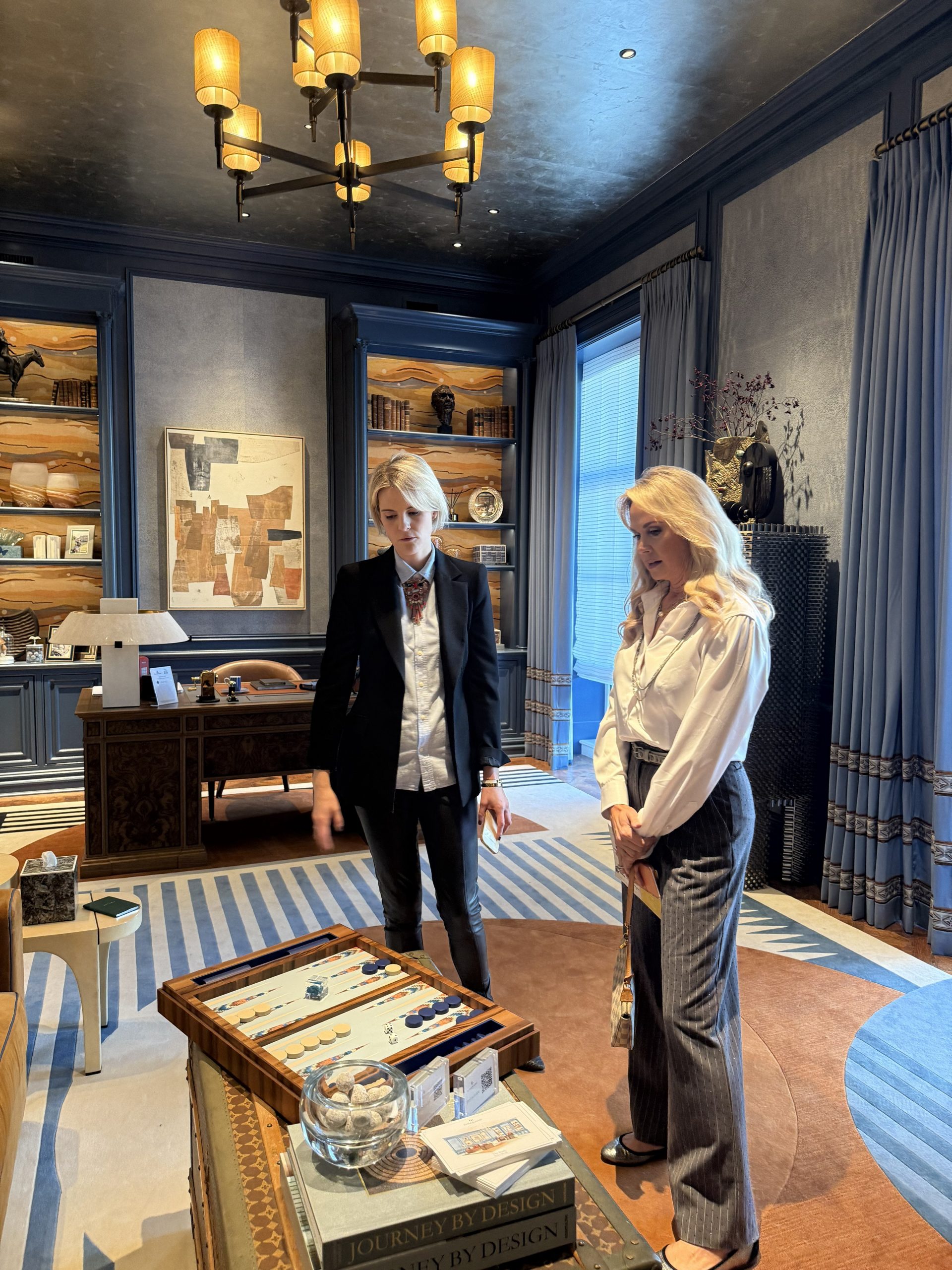 Christine Goodwin speaking with an associate in a sophisticated office space during a Dallas design show house tour.
