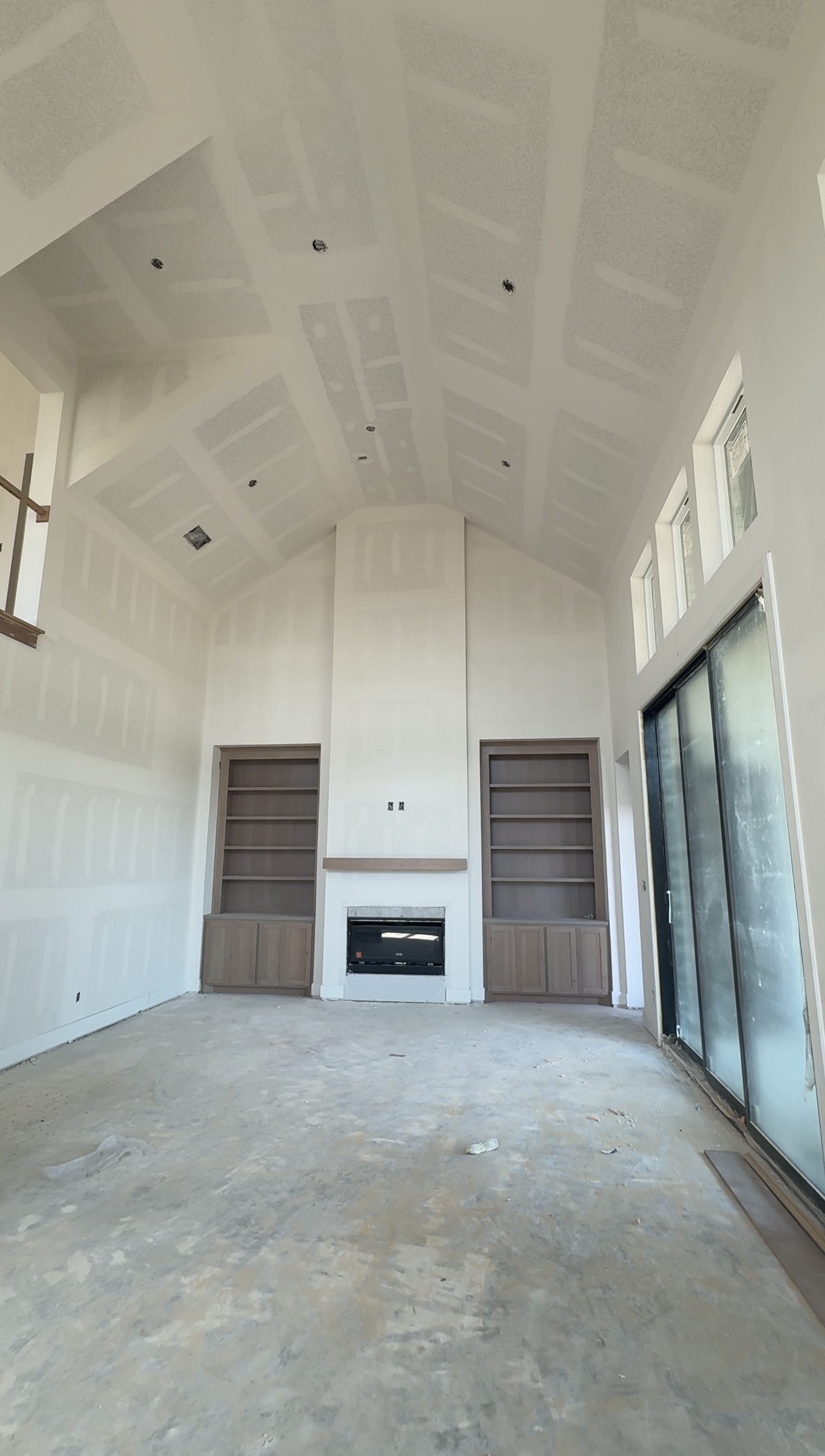 Luxury new construction living room mid build with fireplace and custom shelving