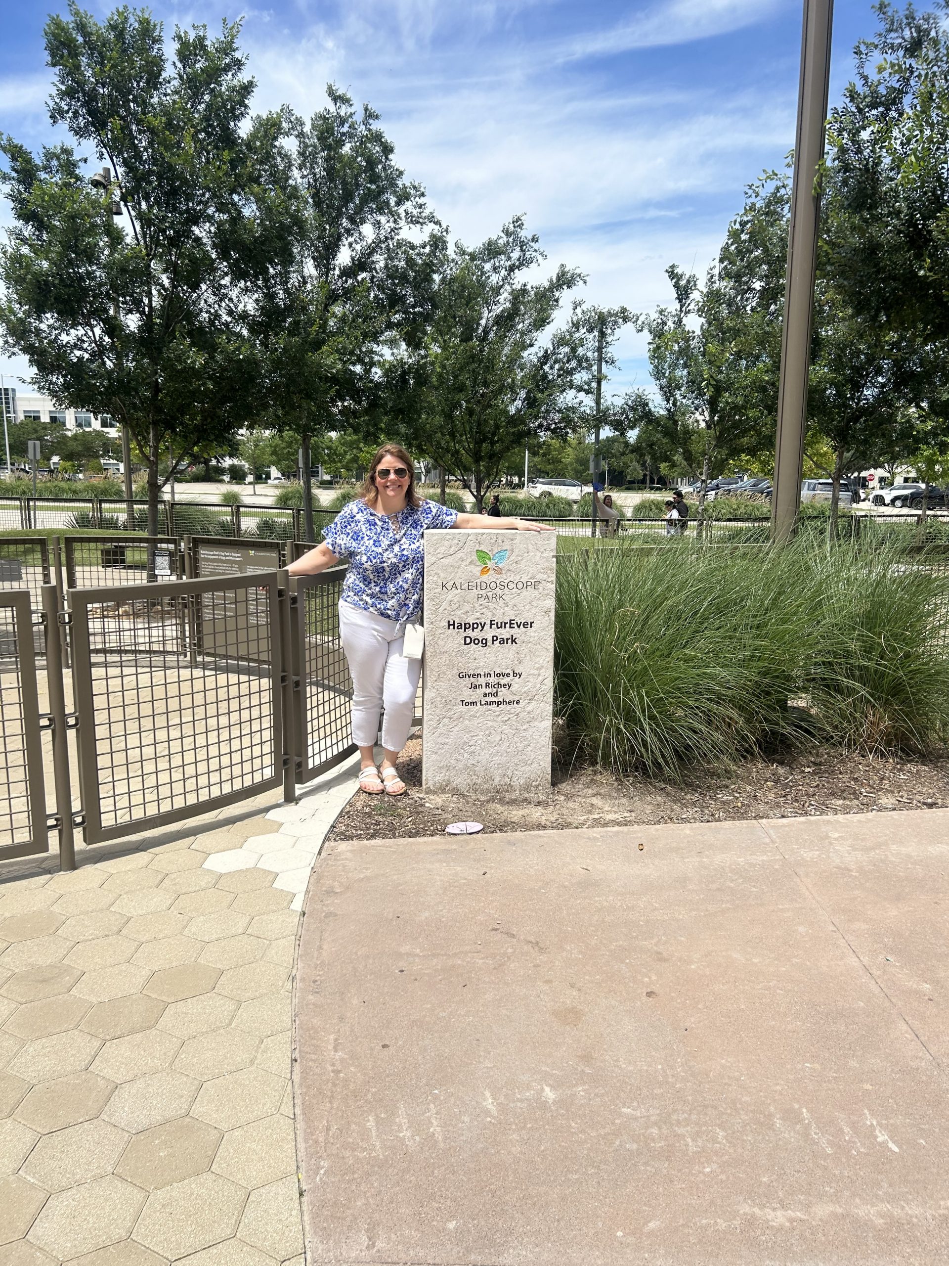 Ali Leali at the Happy FurEver Dog Park sign at Kaleidoscope Park in Frisco, Texas