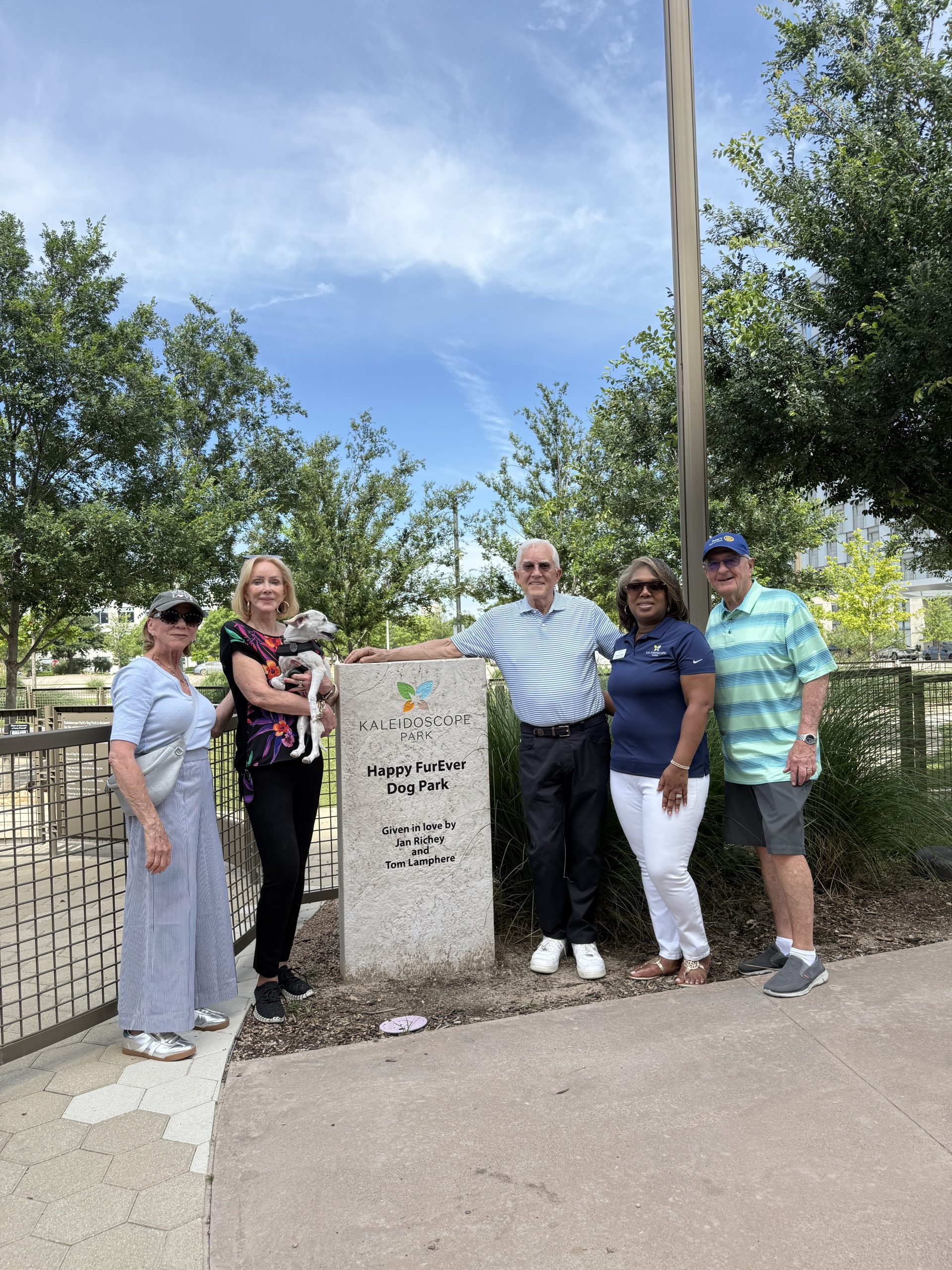Jan Richey, Tom Lamphere, and Kaleidoscope Park representatives at the Happy FurEver Dog Park sign in Frisco, Texas